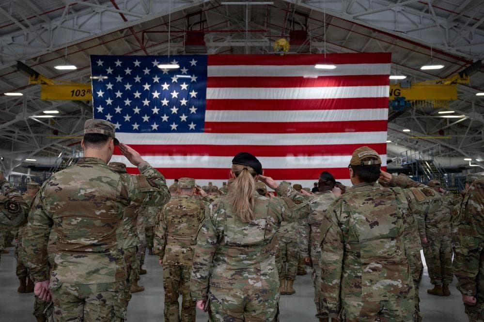 US Soldiers Saluting Large American Flag Inside Hangar