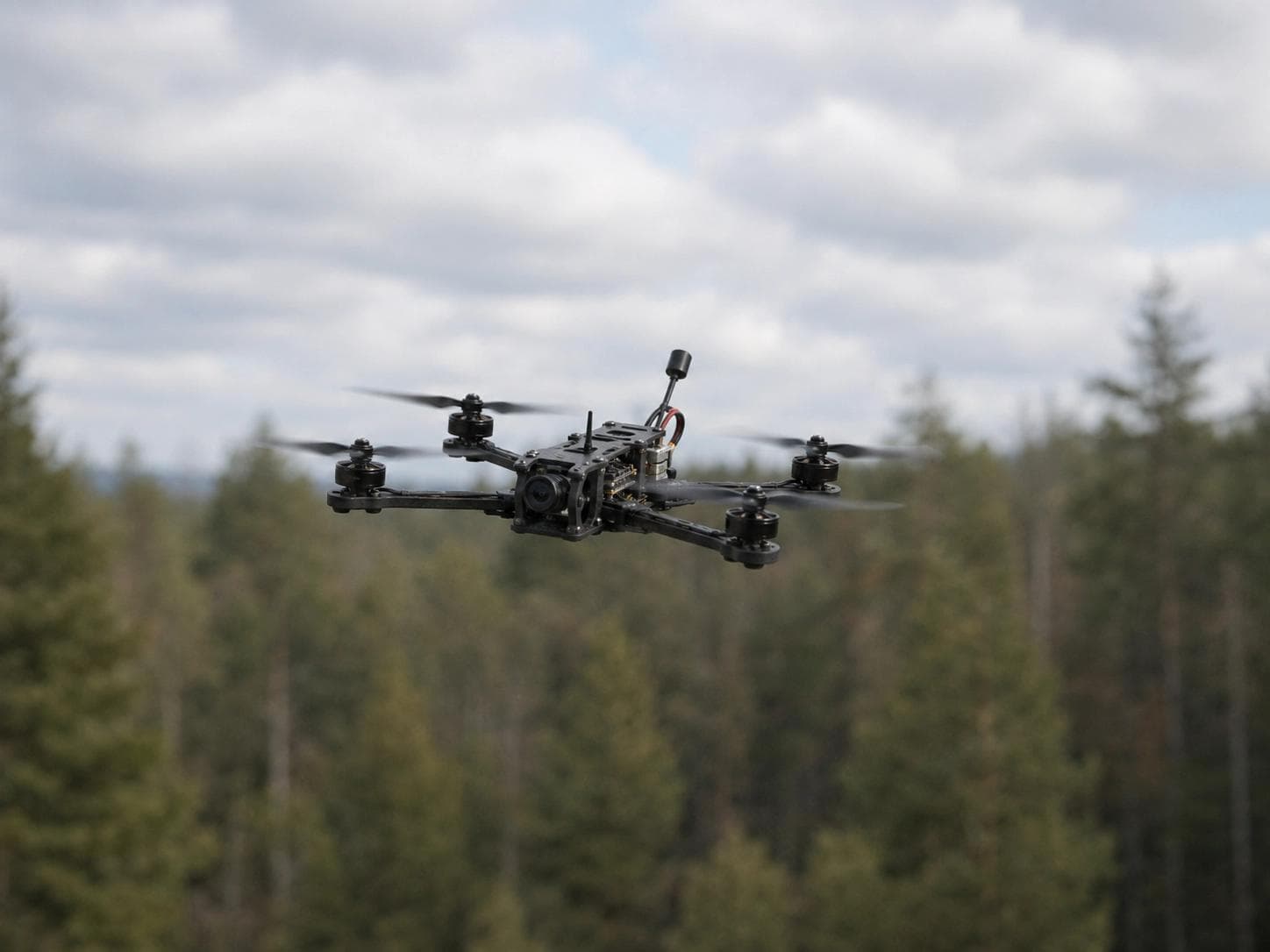 Small FPV racing drone in flight above a pine forest